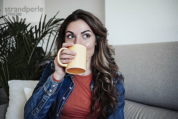Frau mit langen Haaren trinkt zu Hause Kaffee