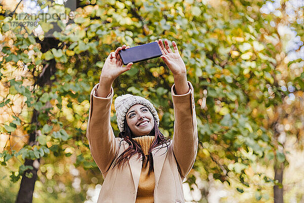 Lächelnde Frau macht Selfie mit Smartphone im Park