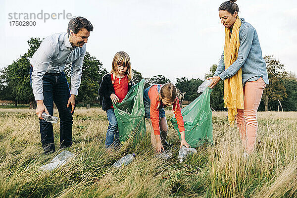 Familie sammelt Plastikflaschen nach Picknick im Park