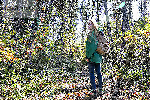 Junge Frau wandert an sonnigem Tag im Wald