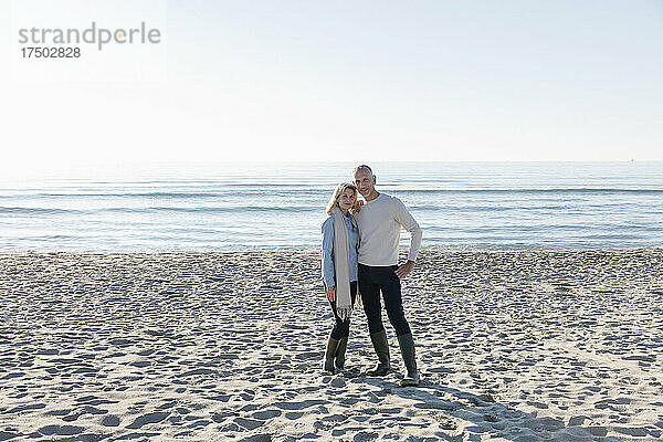 Paar steht zusammen im Sand am Strand