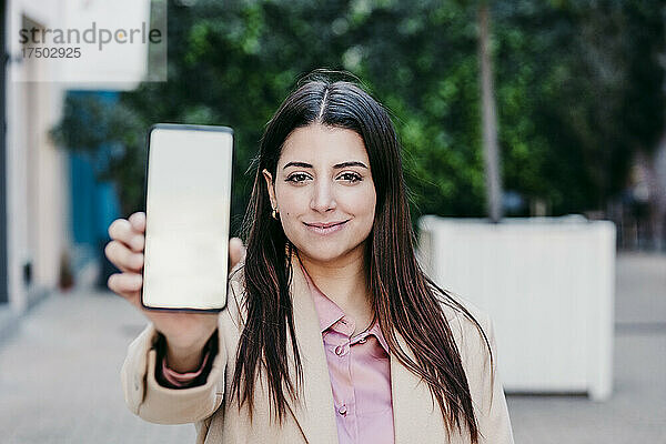 Junge Geschäftsfrau zeigt Mobiltelefon mit leerem Bildschirm