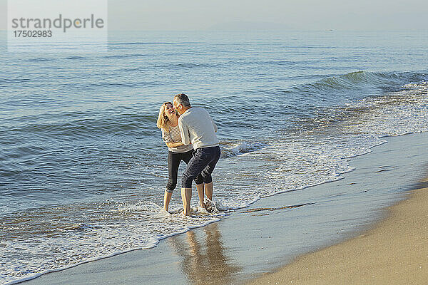 Fröhliches Paar genießt es gemeinsam am Strand