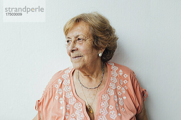 Nachdenkliche ältere Frau vor weißer Wand