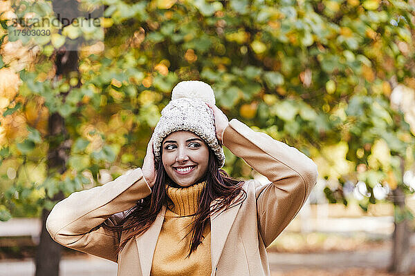 Lächelnde junge Frau mit Strickmütze im Herbstpark