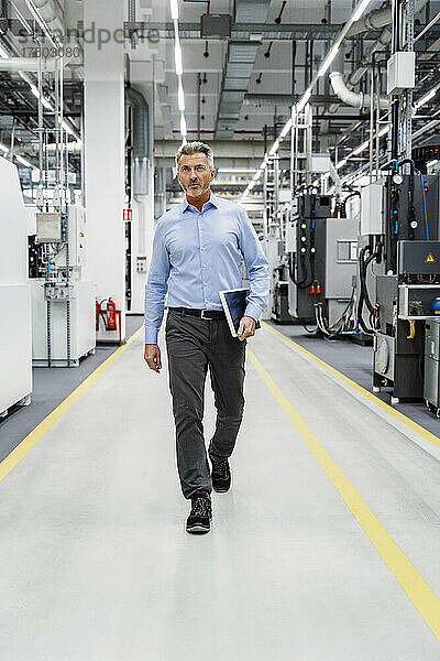 Geschäftsmann mit Tablet-PC in automatisierter Fabrik