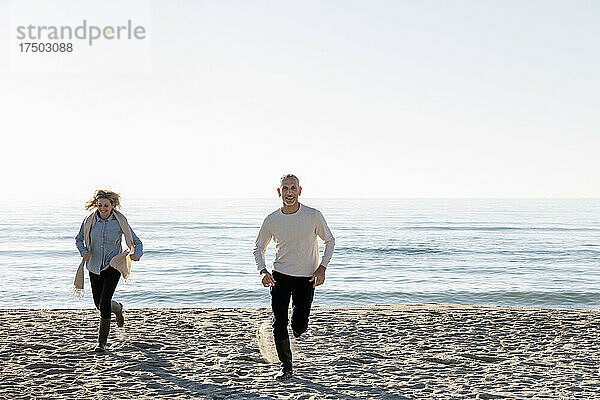 Mann und Frau laufen am Strand auf Sand