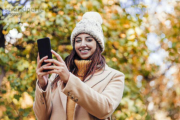 Junge Frau hält Smartphone im Park