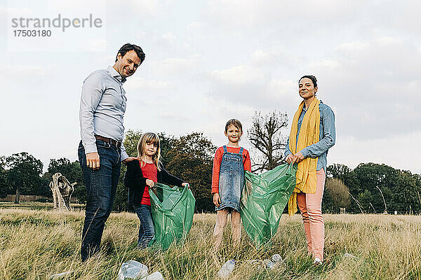 Familie mit Müllsäcken beim Aufräumen im Park