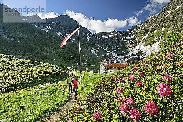 Mann und Frau wandern im Frühling im Virgental mit der Bergerseehütte im Hintergrund