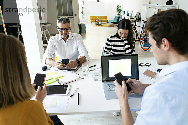 Vielbeschäftigte Kollegen nutzen Smartphones im Büro