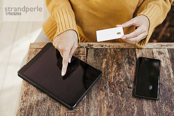 Frau kauft online über ein digitales Tablet am Cafétisch ein