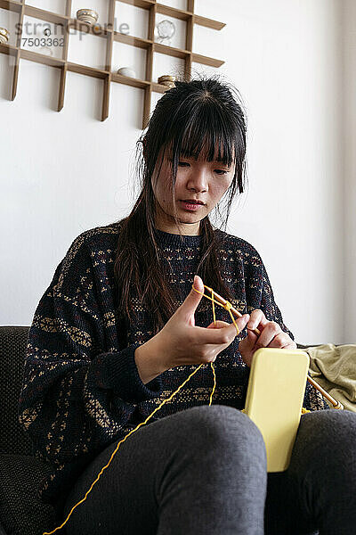 Frau strickt und filmt zu Hause mit dem Handy