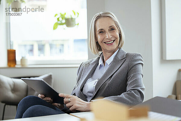 Lächelnde Geschäftsfrau hält Tablet-PC im Büro