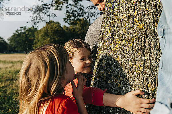 Mädchen umarmt Baum von Eltern und Schwester im Park