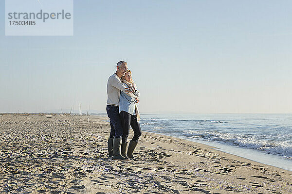 Paar umarmt sich im Sand am Strand