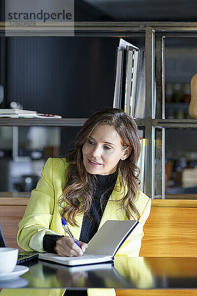Geschäftsfrau schreibt Tagebuch am Tisch im Café