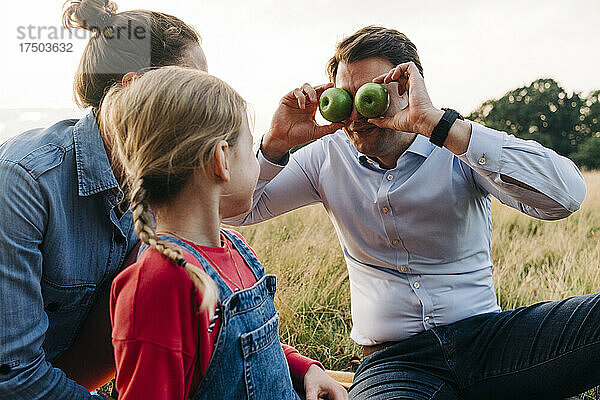 Vater bedeckt Augen mit Früchten  während er mit Tochter im Park spielt