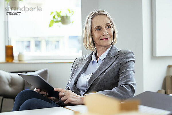Blonde Geschäftsfrau mit Tablet-PC am Arbeitsplatz
