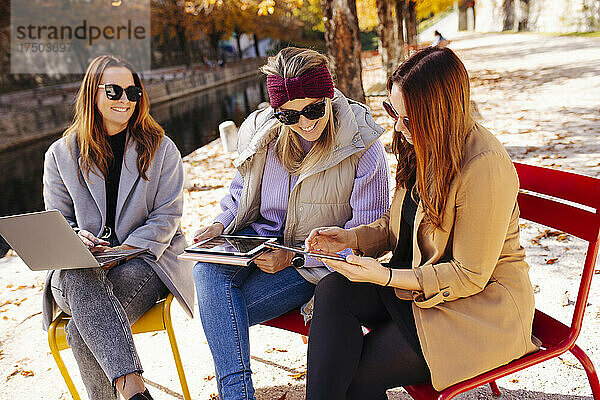 Geschäftsfrau teilt digitales Tablet mit Kollege auf Stuhl