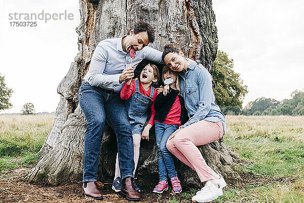 Glückliche Familie genießt Lutscher in der Nähe eines Baumes im Park