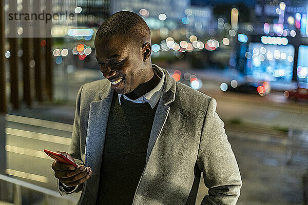 Geschäftsmann benutzt nachts Smartphone in der Stadt