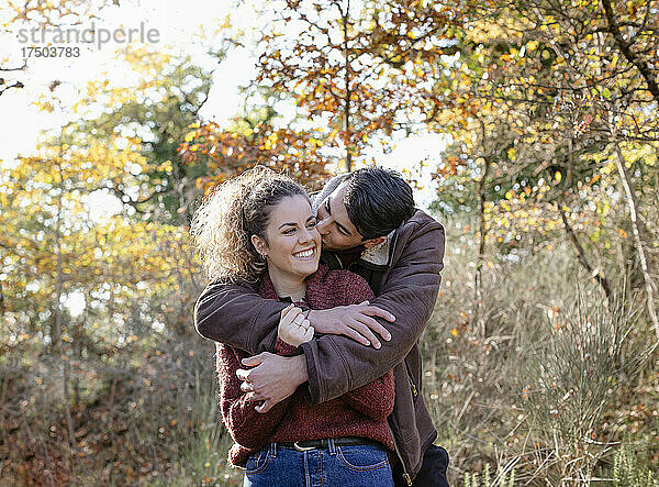 Junger Mann küsst Freundin im Herbstwald