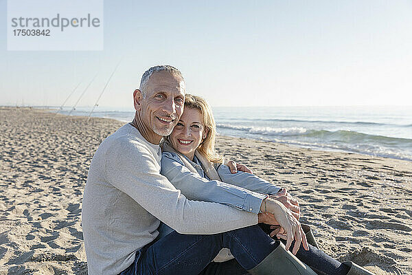 Glückliches Paar sitzt zusammen am Strand