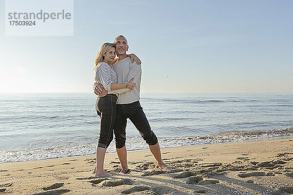 Romantisches Paar steht zusammen im Sand am Strand