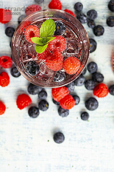 Glas Gin Tonic mit Minze  Eiswürfeln und rohen Beeren