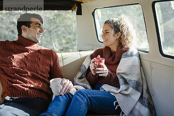 Glückliches Paar beim Kaffeetrinken im Van am Wochenende