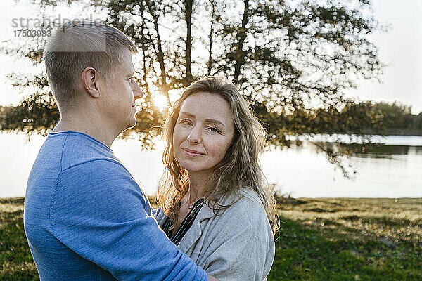 Mann umarmt blonde Frau im Park bei Sonnenuntergang