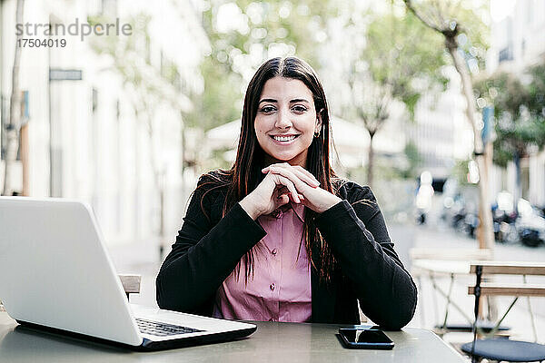 Junge Geschäftsfrau mit Laptop im Straßencafé