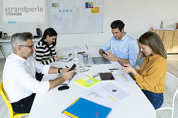 Kollegen nutzen Smartphones am Schreibtisch im Büro