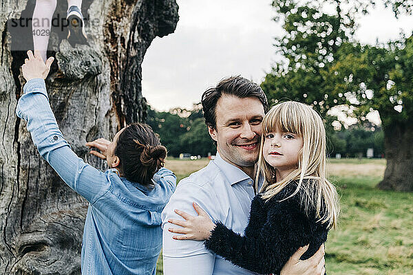 Lächelnder Vater trägt Tochter im Park