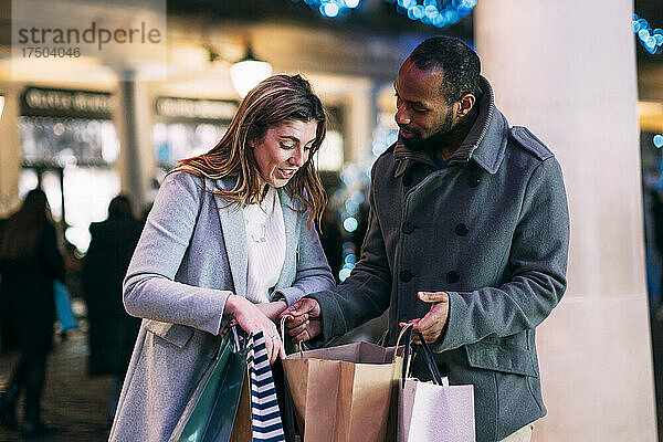 Frau diskutiert mit Mann  der Einkaufstüten auf dem Weihnachtsmarkt hält