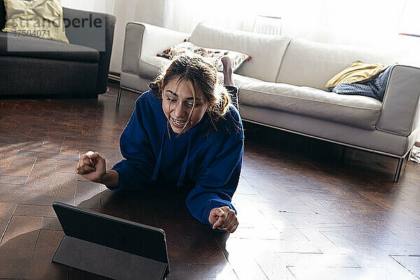Glückliche Frau jubelt und benutzt Tablet-PC zu Hause