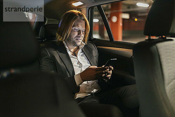 Geschäftsmann benutzt nachts Mobiltelefon im Auto