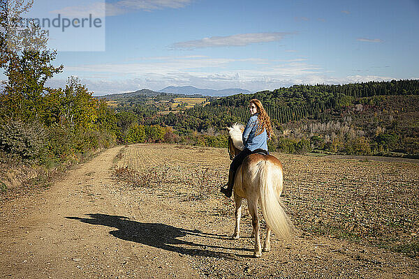 Junge Frau reitet an sonnigem Tag auf der Ranch
