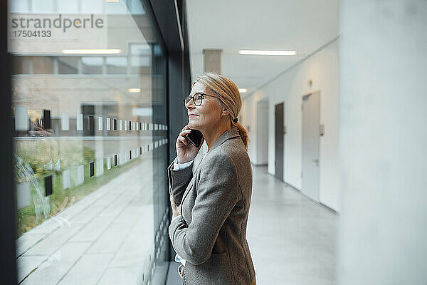 Geschäftsfrau telefoniert im Büroflur mit dem Mobiltelefon