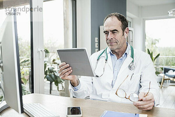 Arzt starrt auf digitales Tablet in medizinischer Klinik