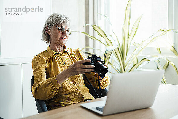 Geschäftsfrau mit Brille überprüft Kamera im Büro