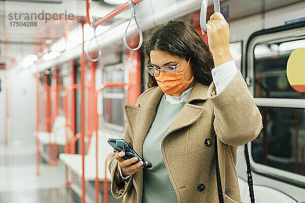 Kurvige Frau benutzt während einer Pandemie ihr Mobiltelefon im Zug