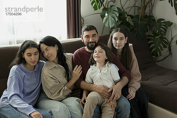 Lächelnde Familie sitzt zu Hause zusammen auf dem Sofa