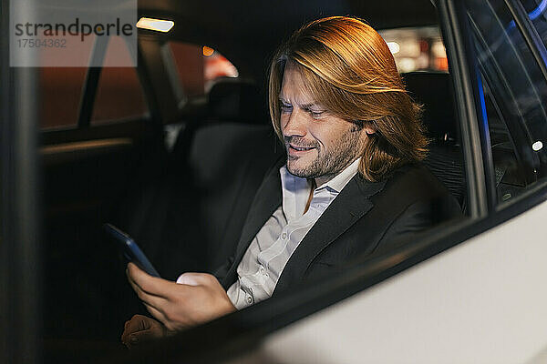 Geschäftsmann benutzt nachts Smartphone im Auto