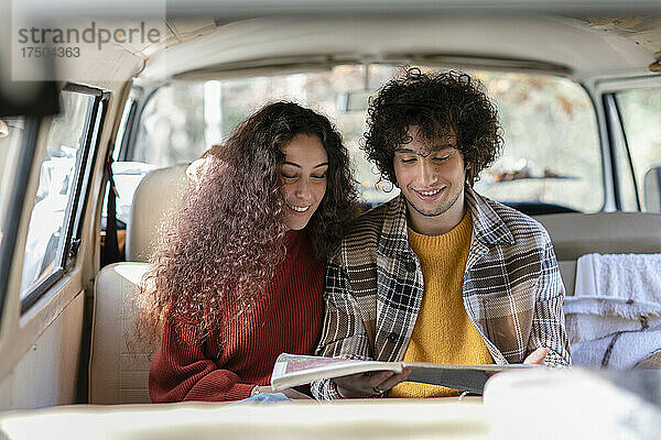 Lächelndes Paar liest am Wochenende Mann im Wohnmobil