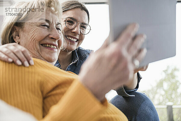 Lächelnde Frauen  die zu Hause einen Tablet-PC nutzen