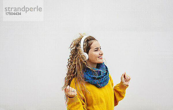 Lächelnde Frau  die Musik über Kopfhörer auf weißem Hintergrund genießt