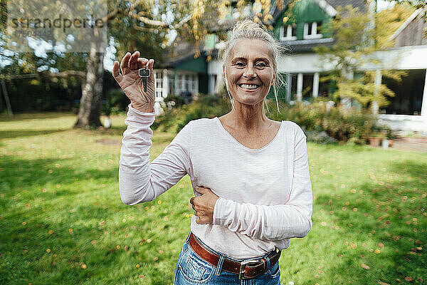 Glückliche Frau hält Hausschlüssel im Hinterhof