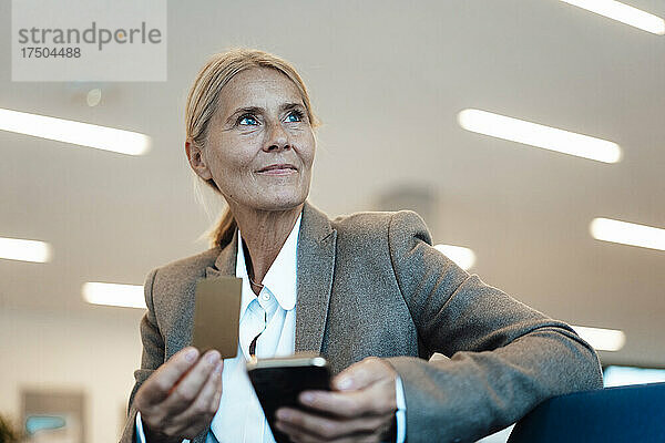 Geschäftsfrau hält Kreditkarte und Mobiltelefon im Büro